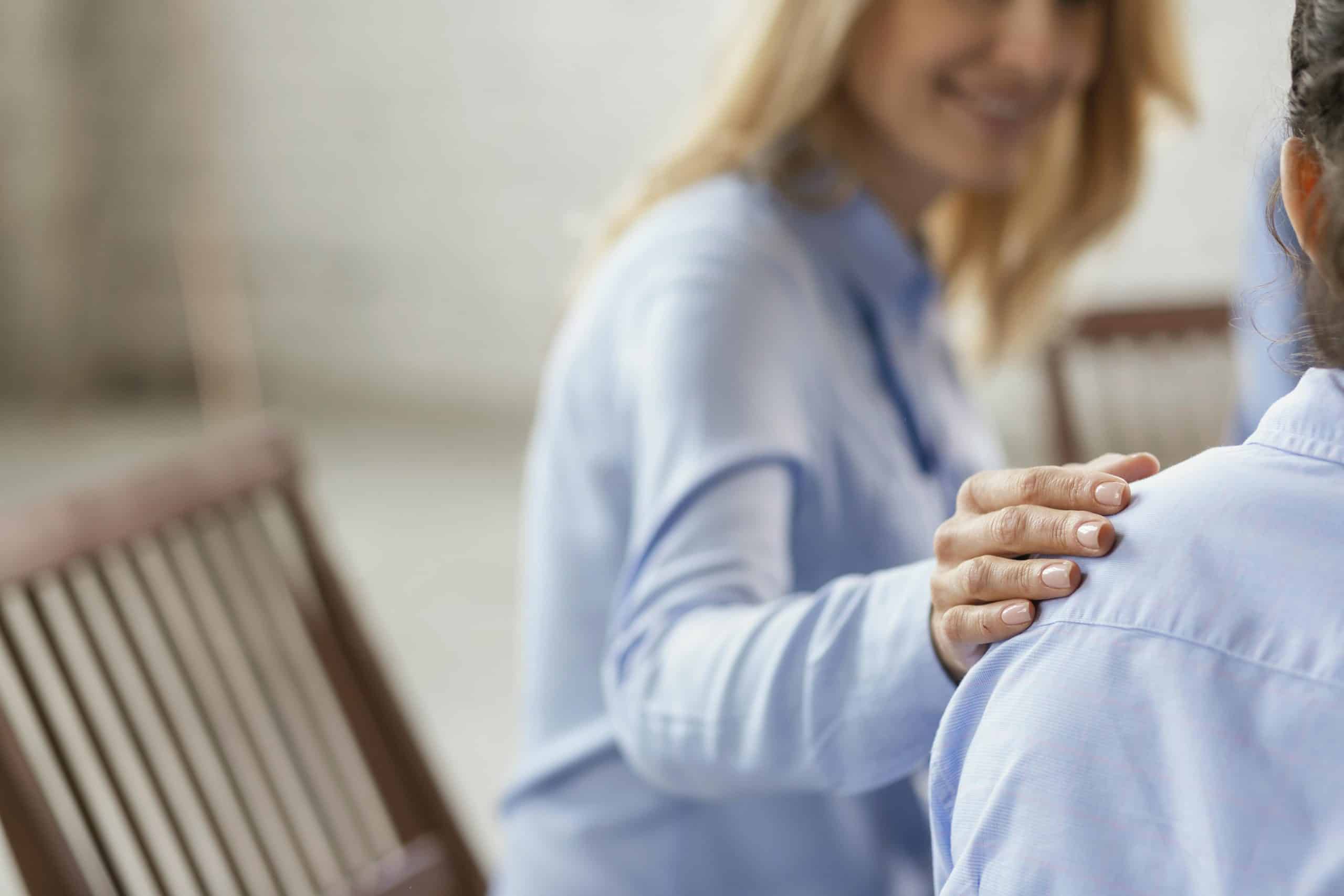 Eine Frau hält die Hand auf der Schulter einer anderen.
